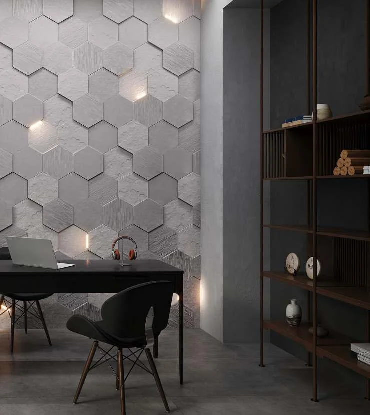 Modern interior office space with hexagonal tiled wall, black desk, chair, and a bookshelf with decorative items.