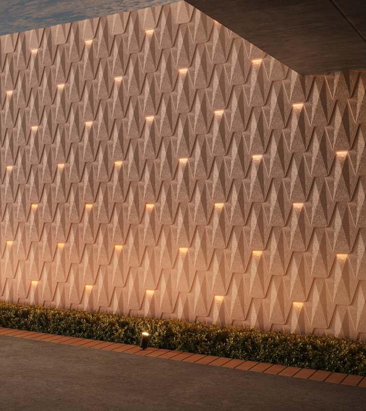 Decorative wall with a geometric 3D pattern and integrated lighting, accented by a neatly trimmed hedge along the base.