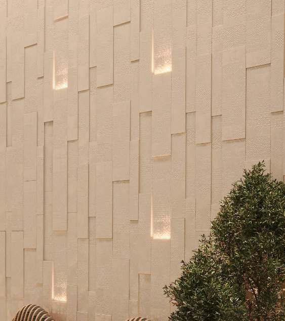Interior wall with a textured beige surface and embedded rectangular light panels, with a green leafy plant in the lower right corner.