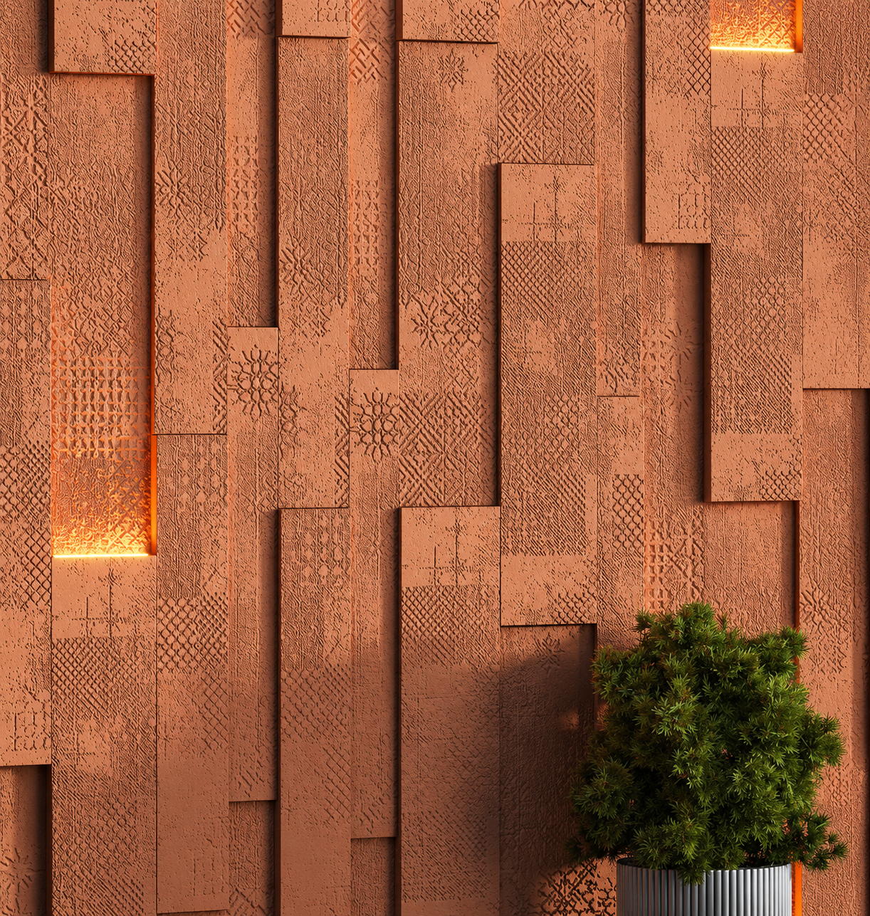 Decorative terracotta wall with textured geometric patterns and cutouts, illuminated with warm lighting, with a green potted plant at the bottom right.