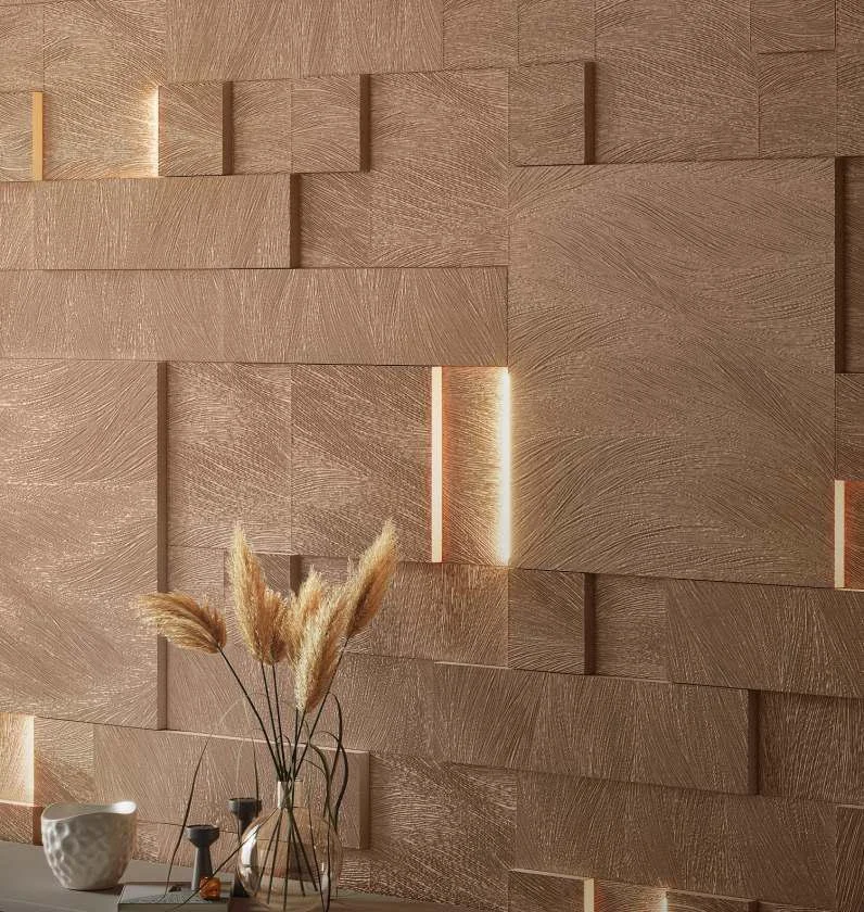 Close-up of a textured wooden wall with layered panels and integrated lighting, decorated with a clear vase holding dried pampas grass and a white textured ceramic cup on a surface.