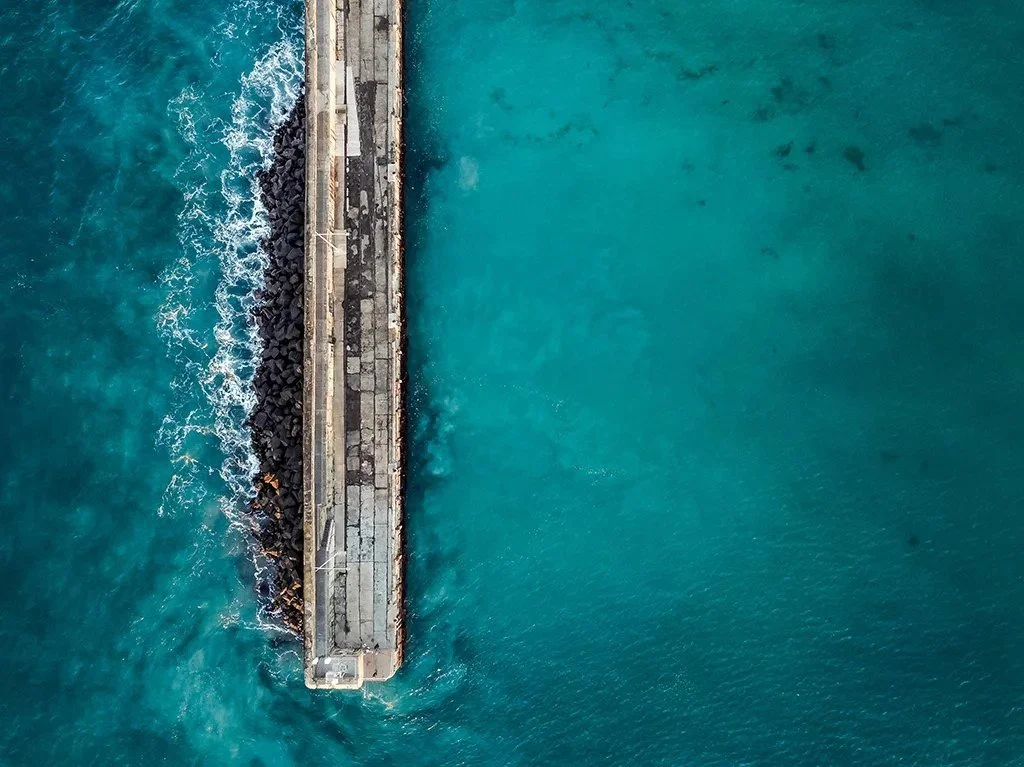 Aerial view of the Warrnambool coastline with a pier dividing blue ocean waters