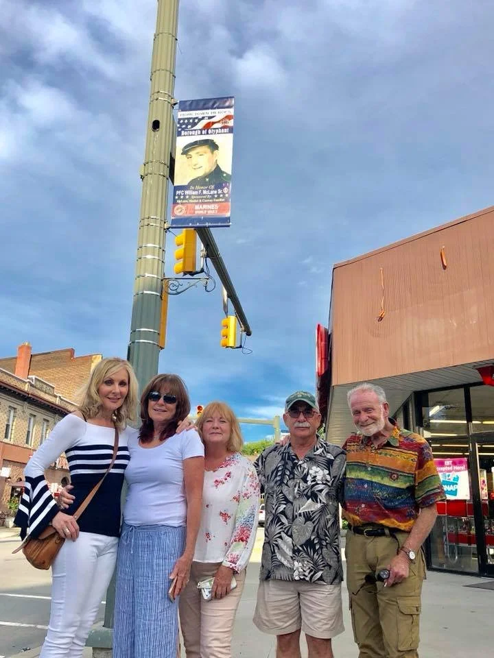 Judy and her siblings in their hometown of Olyphant, PA, under their dad's salute to Veteran's flag