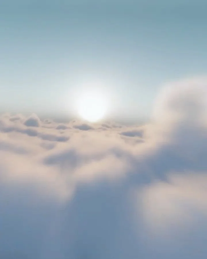 Sun rising above soft, fluffy clouds in the sky