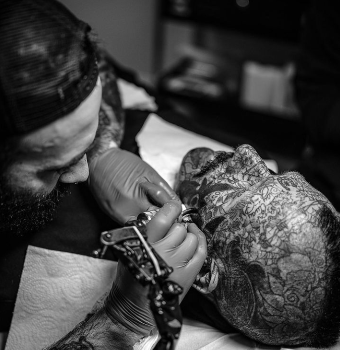 A tattoo artist working on a person's arm in a tattoo shop.