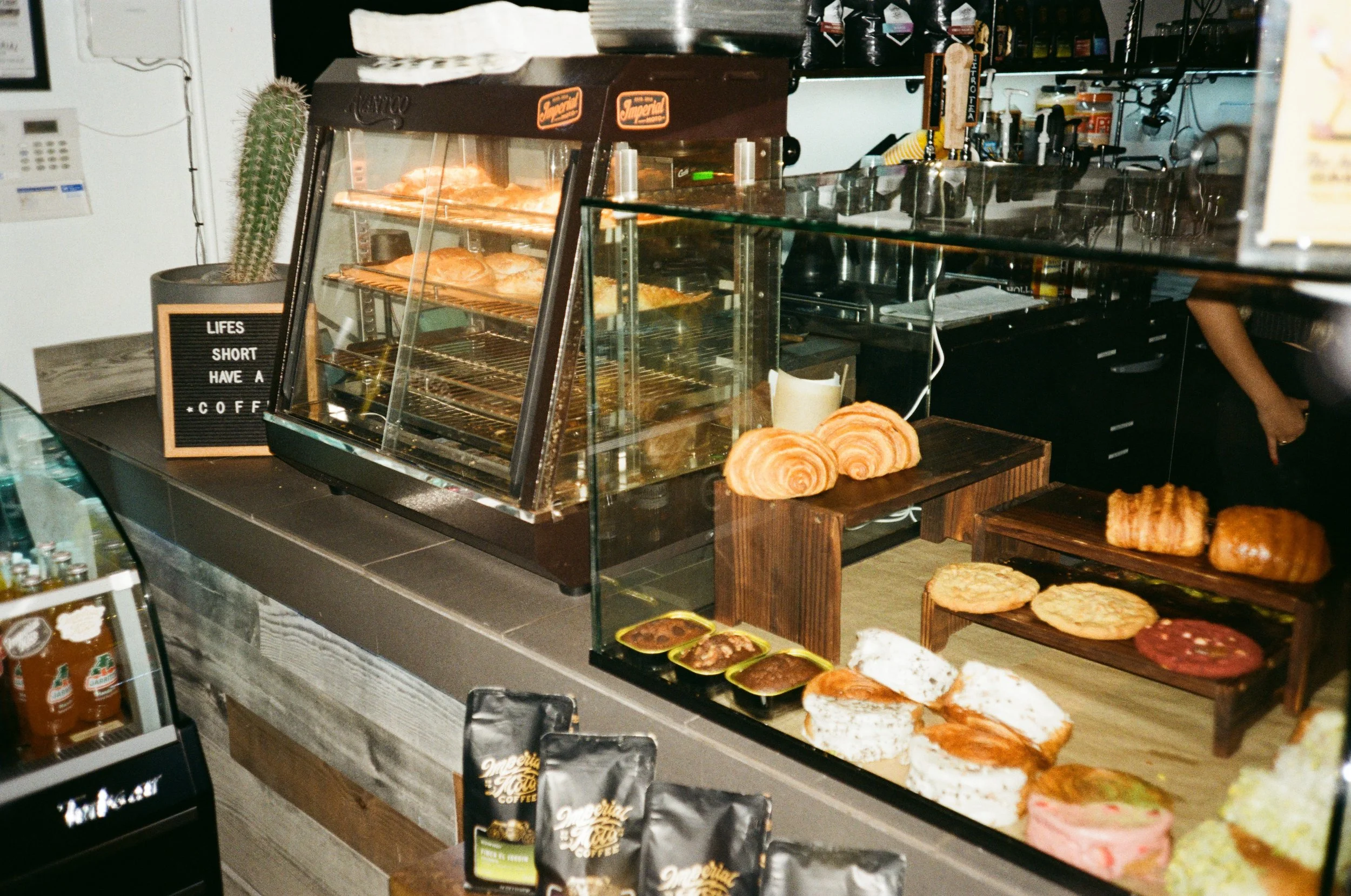 Display case with assorted baked goods including croissants, bread, and cookies in a cafe.