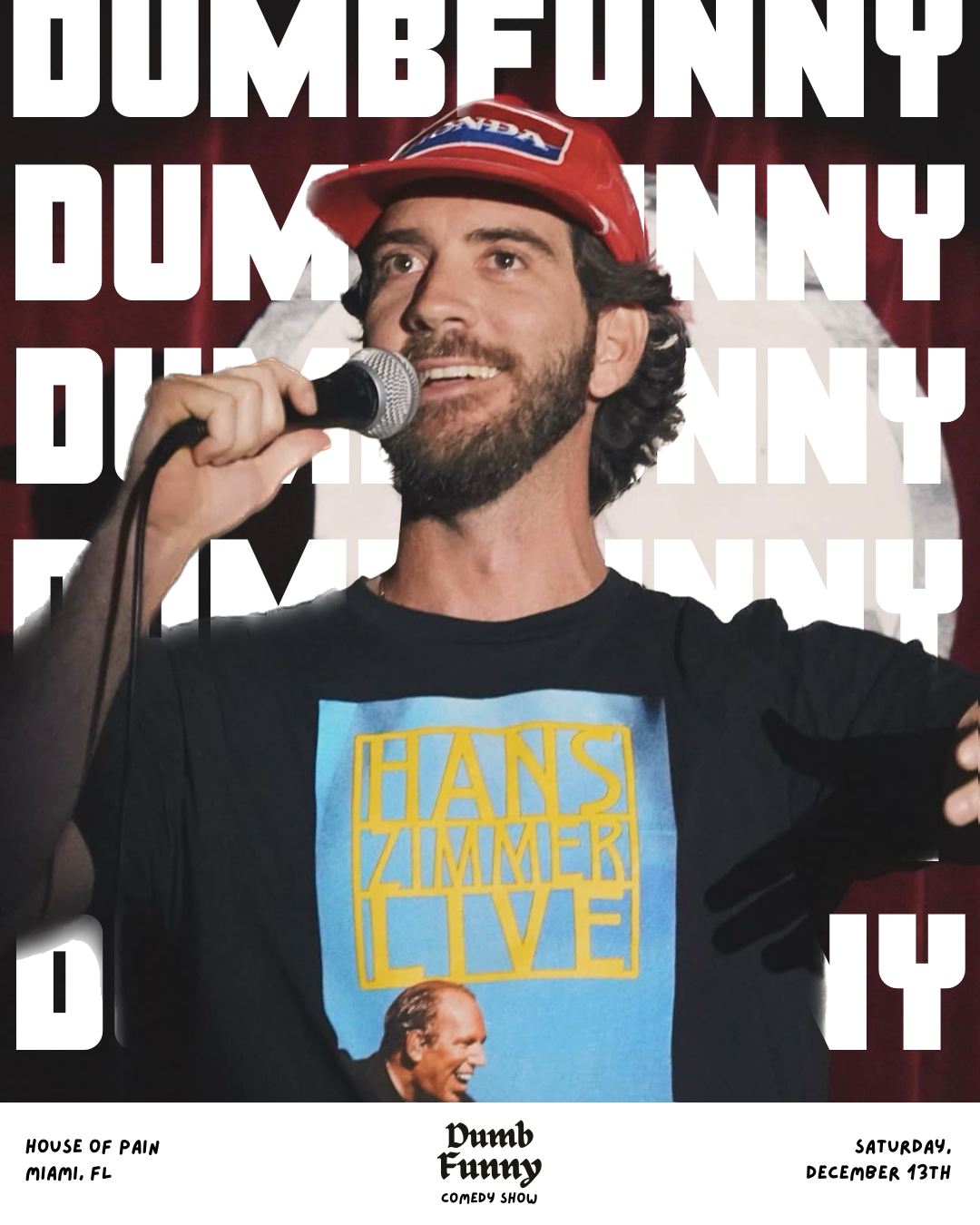 A man with dark hair and a beard is holding a microphone on stage, wearing a red cap with a logo, and a black T-shirt with a picture and text design. The background shows a red curtain with bold white text overlaying the image.