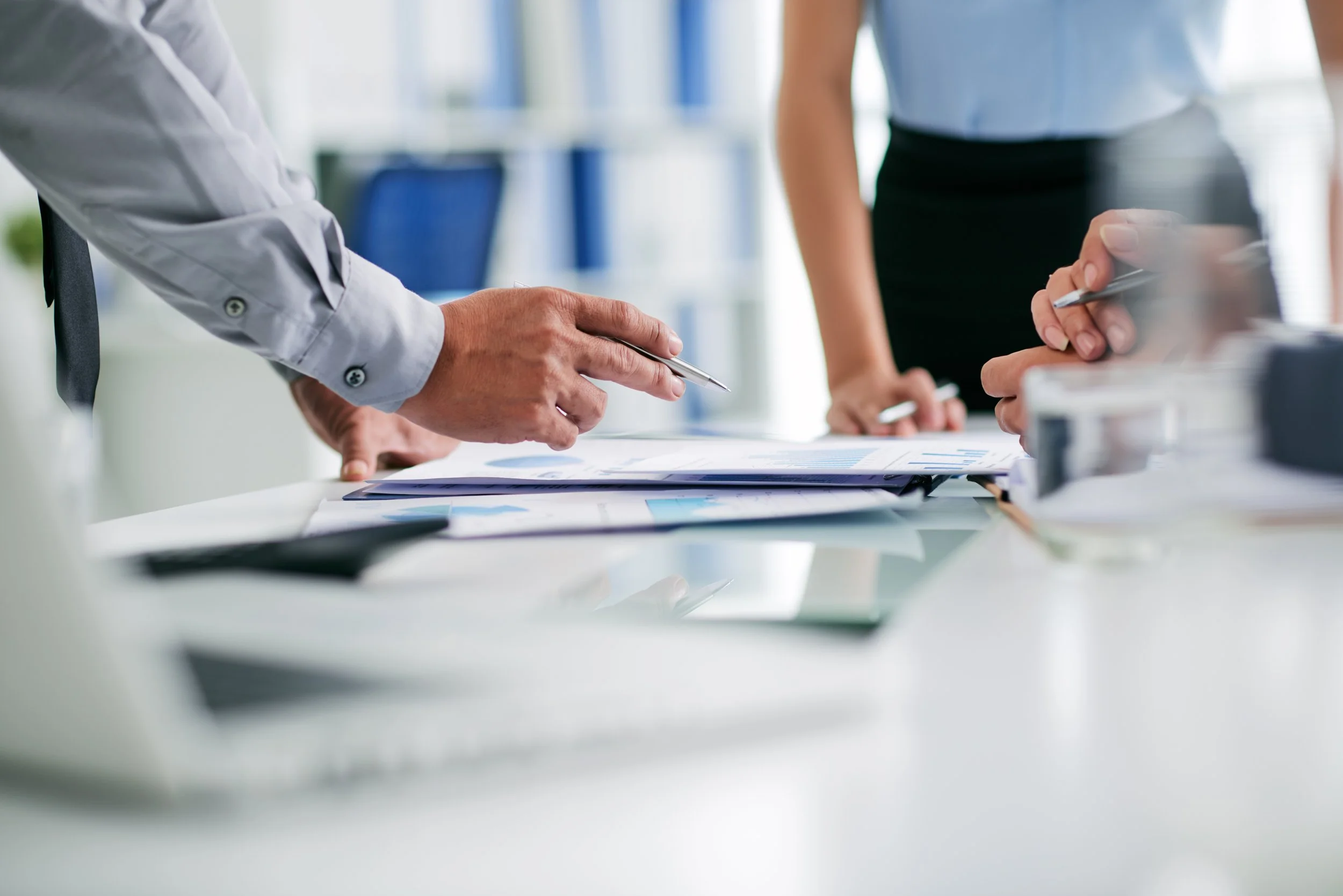 Two people discussing documents and charts in a modern office.