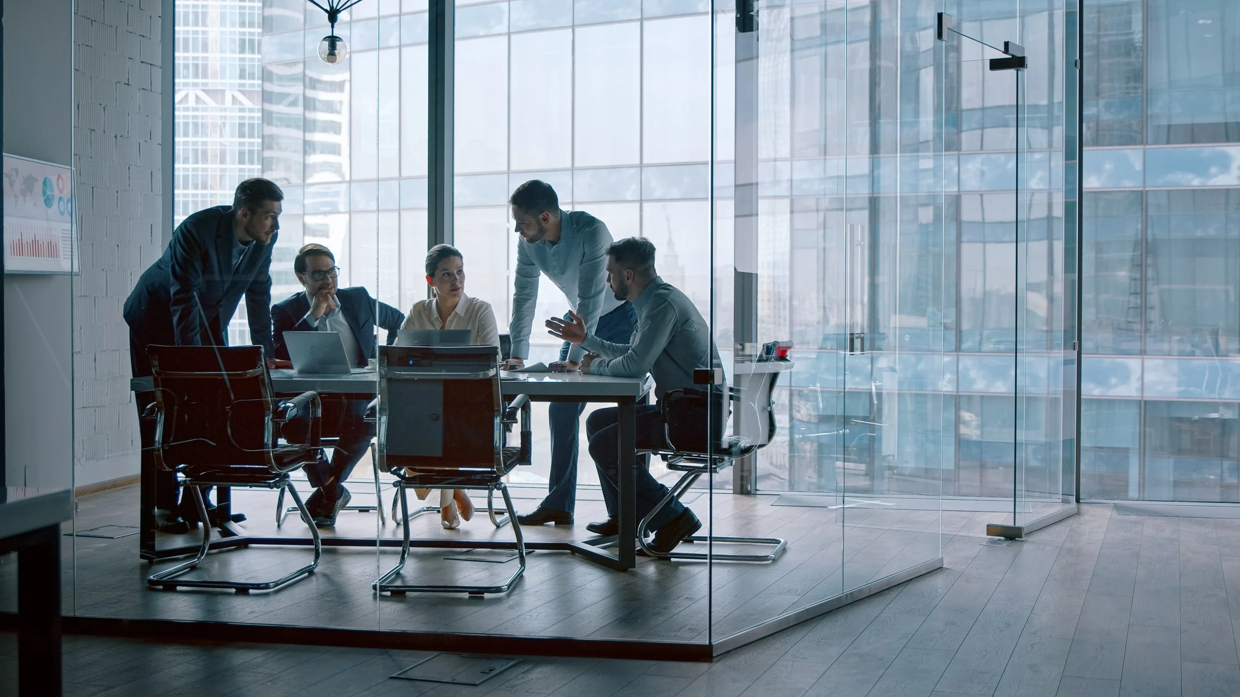 Business team in a modern conference room with large glass windows during a meeting.
