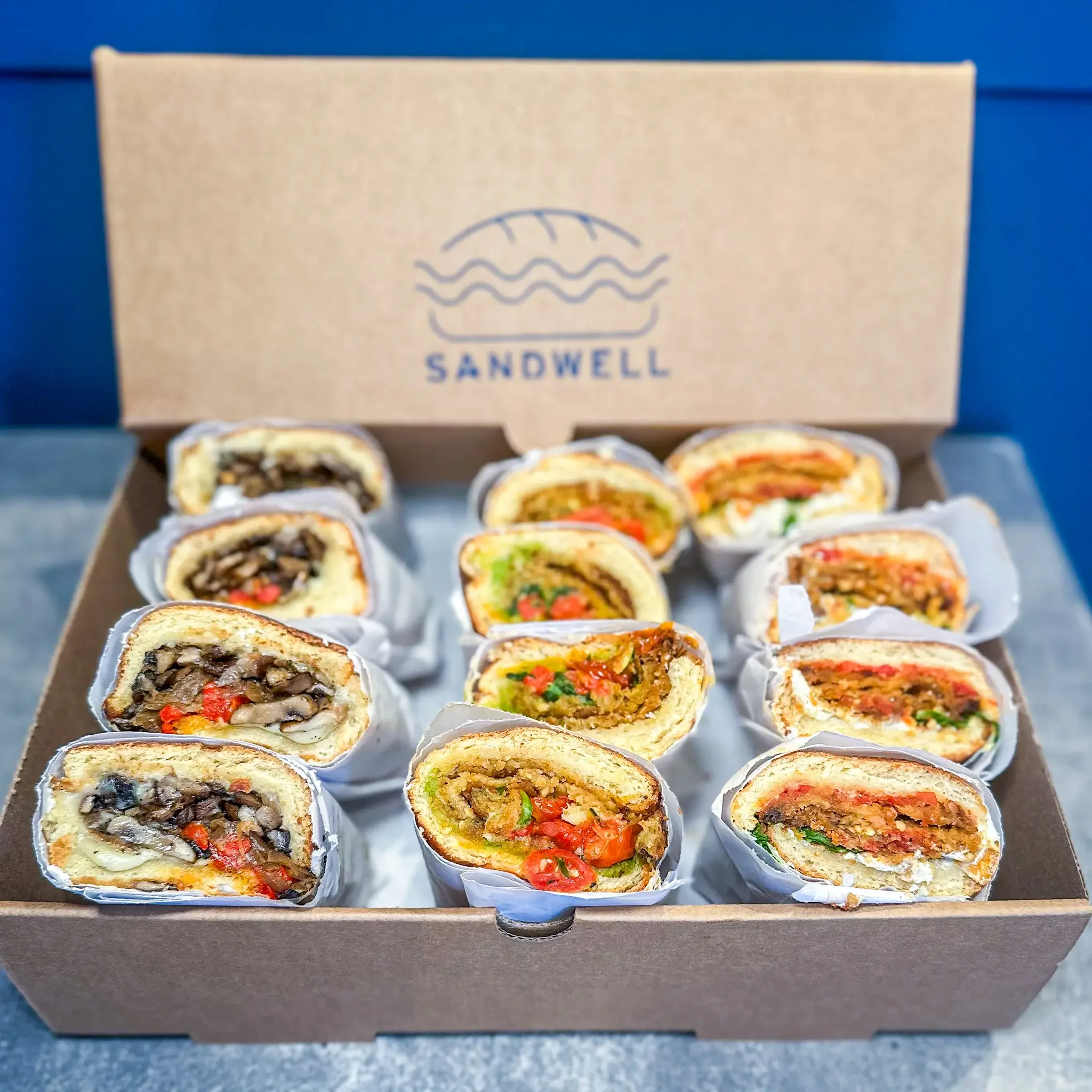 Sandwell's Veggies Sandwich Box for catering — featuring Mushroom Cheese"steak", Spicy Eggplant Parm, and The Remy vegan sandwich on house-baked semolina bread, available in NYC