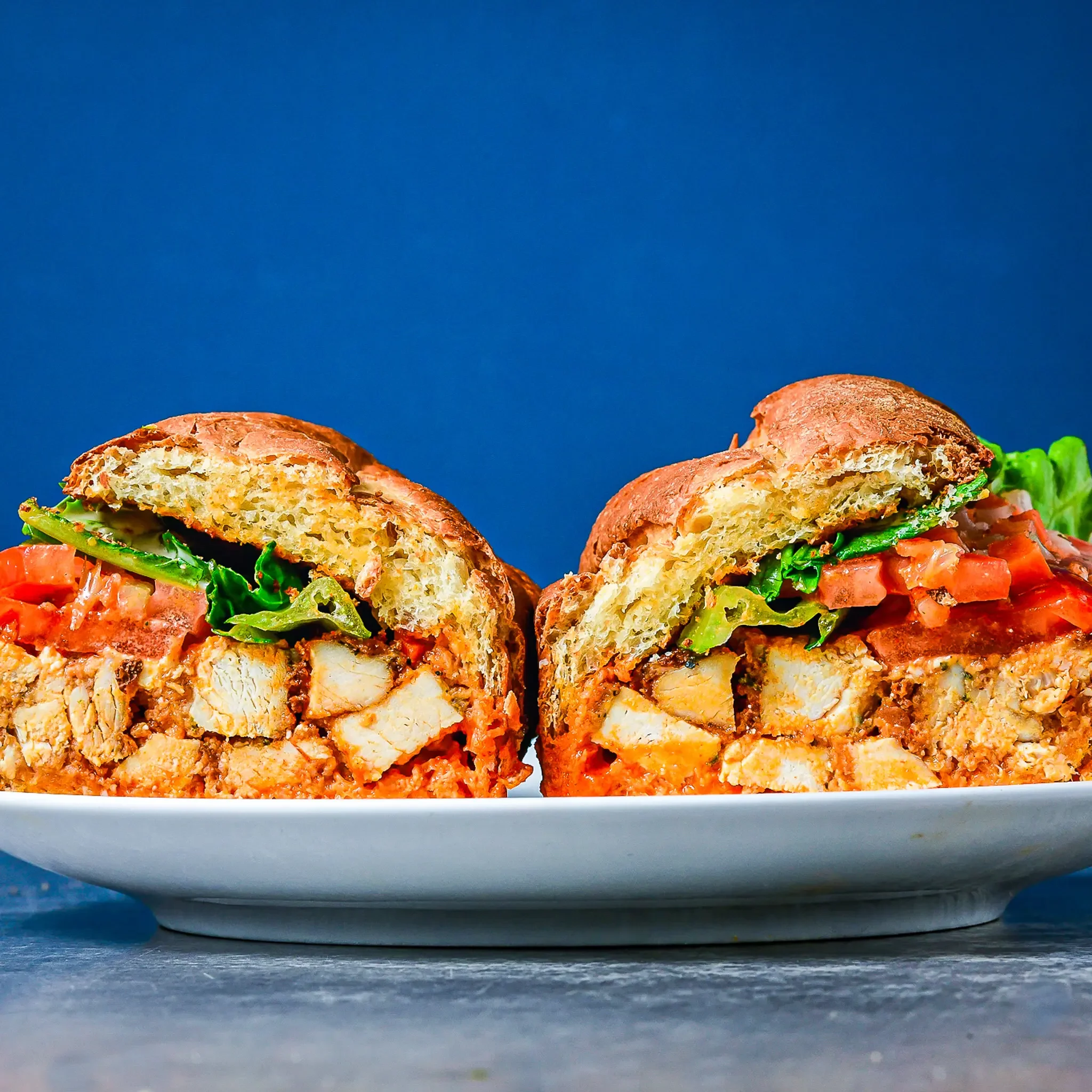 Sandwell's Buffalo Chicken sub — baked chicken cutlet with buffalo sauce, blue cheese, pickled carrots and celery, lettuce, tomato, and dairy-free avocado ranch on a house-baked semolina roll, available at Sandwell sandwich shops in NYC