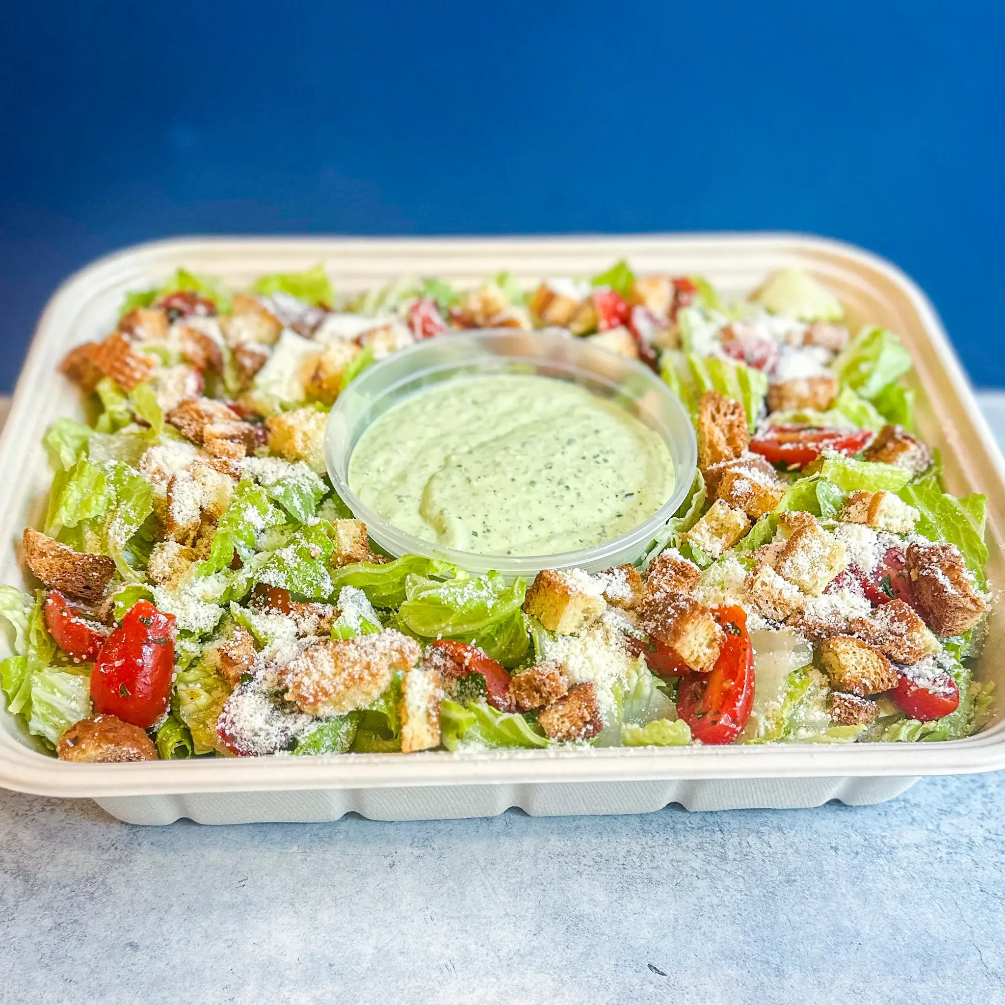 Mixed Green Salad Tray with fresh mixed greens, herb-marinated cherry tomatoes with secret spice seasoning, and vegan maple dijon vinaigrette, available for catering at Sandwell sandwich shops in NYC