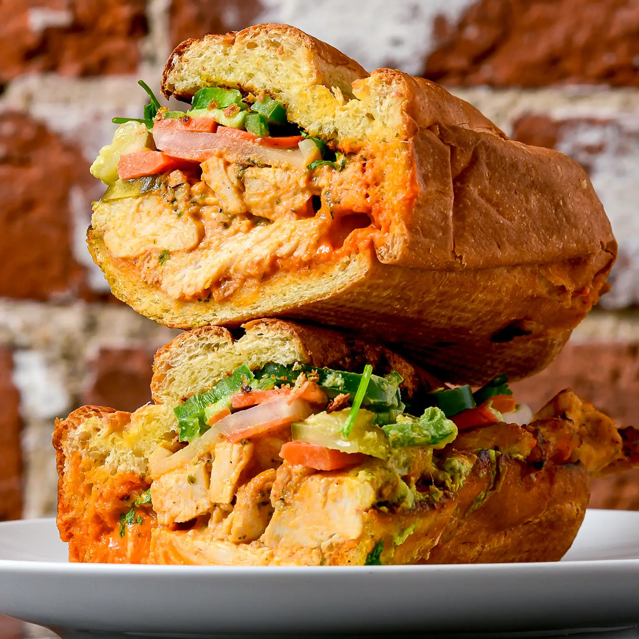 Würziges Hähnchen-Banh Mi mit Zitronengras-Hähnchen, hausgemachtem eingelegtem Gemüse, Koriander, Sriracha-Coulis und Jalapeño-Aioli auf hausgebackenem Grießbrot, erhältlich in den Sandwell-Sandwich-Läden in NYC