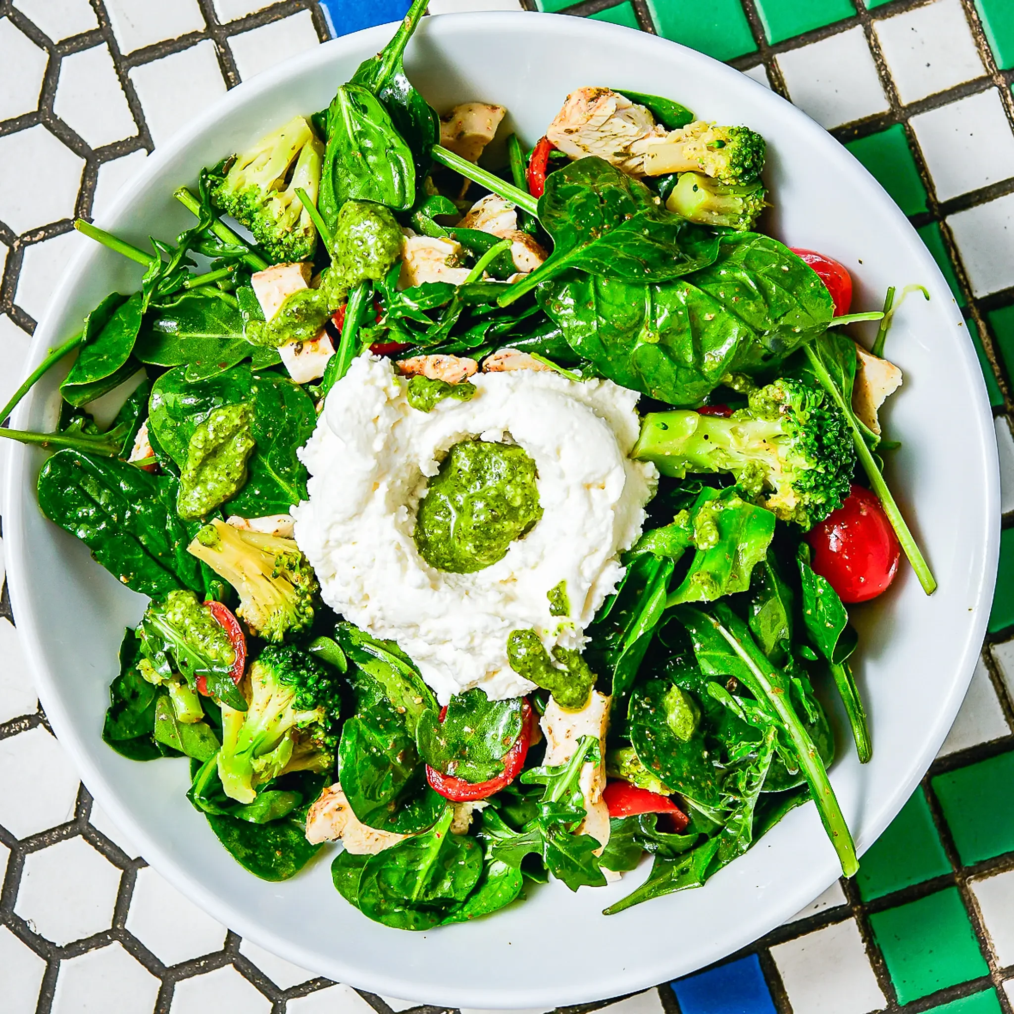 Sandwell's Pesto Chicken Salad — grilled chicken breast with whipped burrata, spinach, arugula, cherry tomatoes, broccoli, and pesto vinaigrette, available at Sandwell sandwich shops in NYC