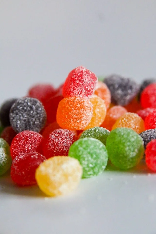 A colorful assortment of sugar-coated fruit gummy candies in various vibrant colors like red, orange, green, and yellow.