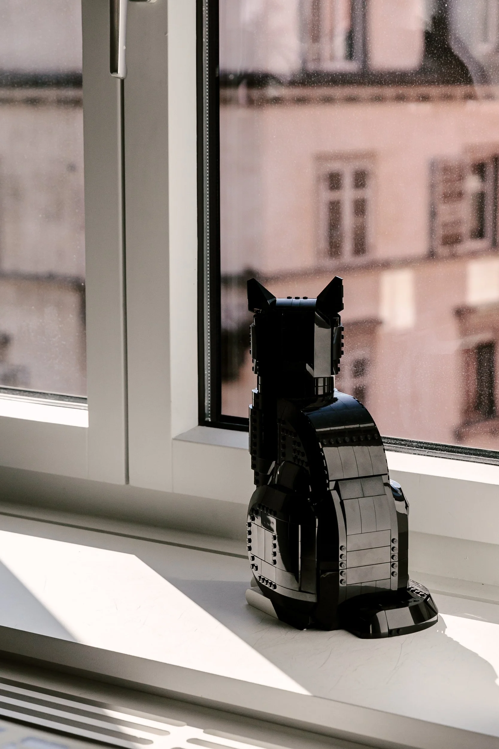 Ein schwarze Lego-Figur in Form einer Katze auf einem Fensterbrett.