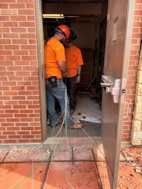 Two electricians pulling wire through a doorway