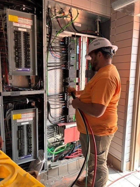 An electrician about to feed wires into a panel