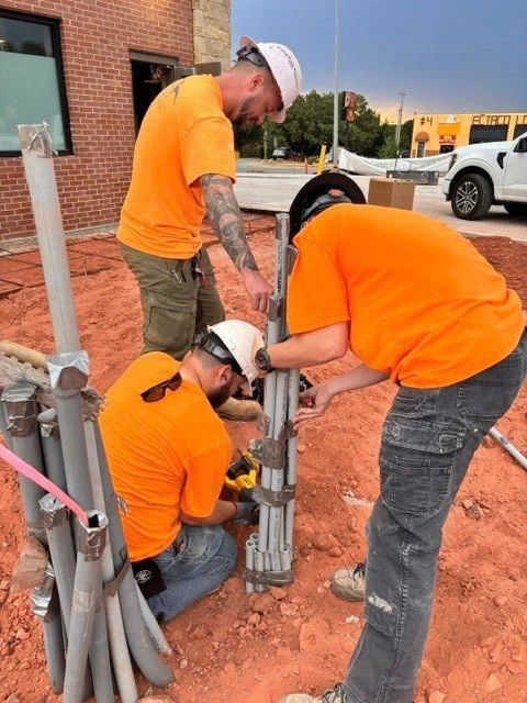 Three electricians working to cut PVC pipes