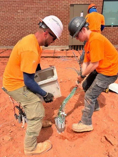 Two electricians placing a quazite box