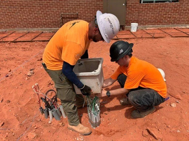 Two electricians placing a quazite box