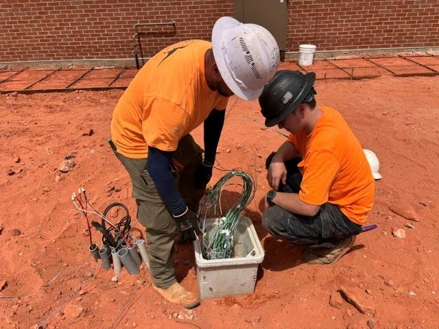Two electricians placing a quazite box