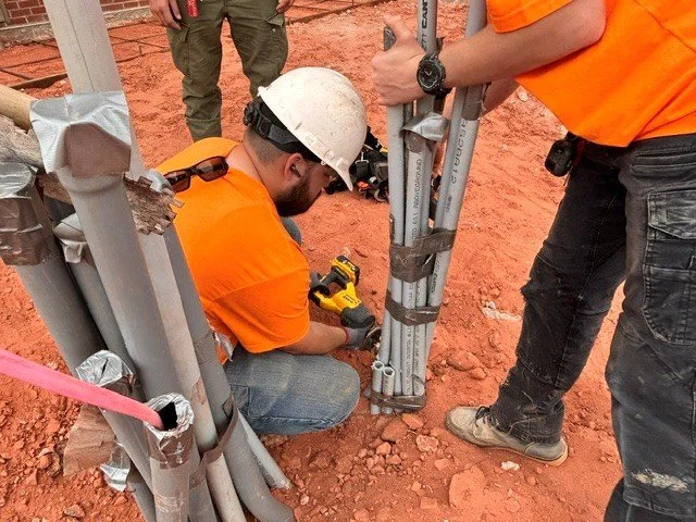 Two electricians cutting PVC pipes
