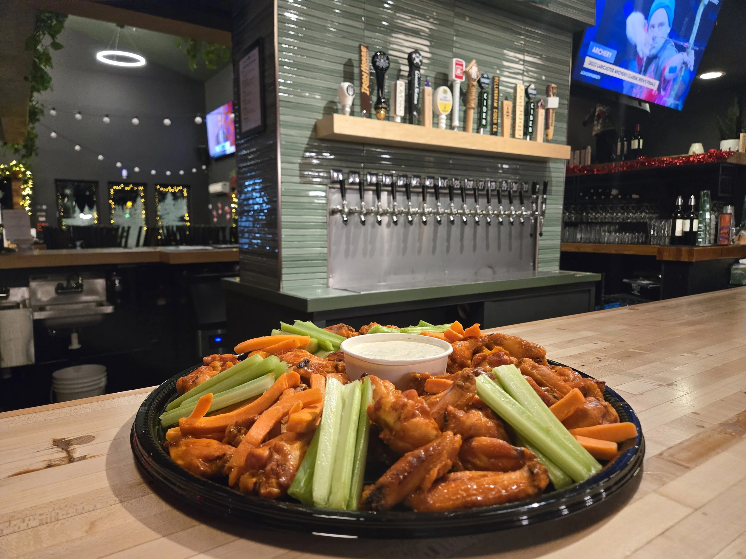 Plate of buffalo chicken wings with celery and carrot sticks served with ranch dressing in a bar or pub setting