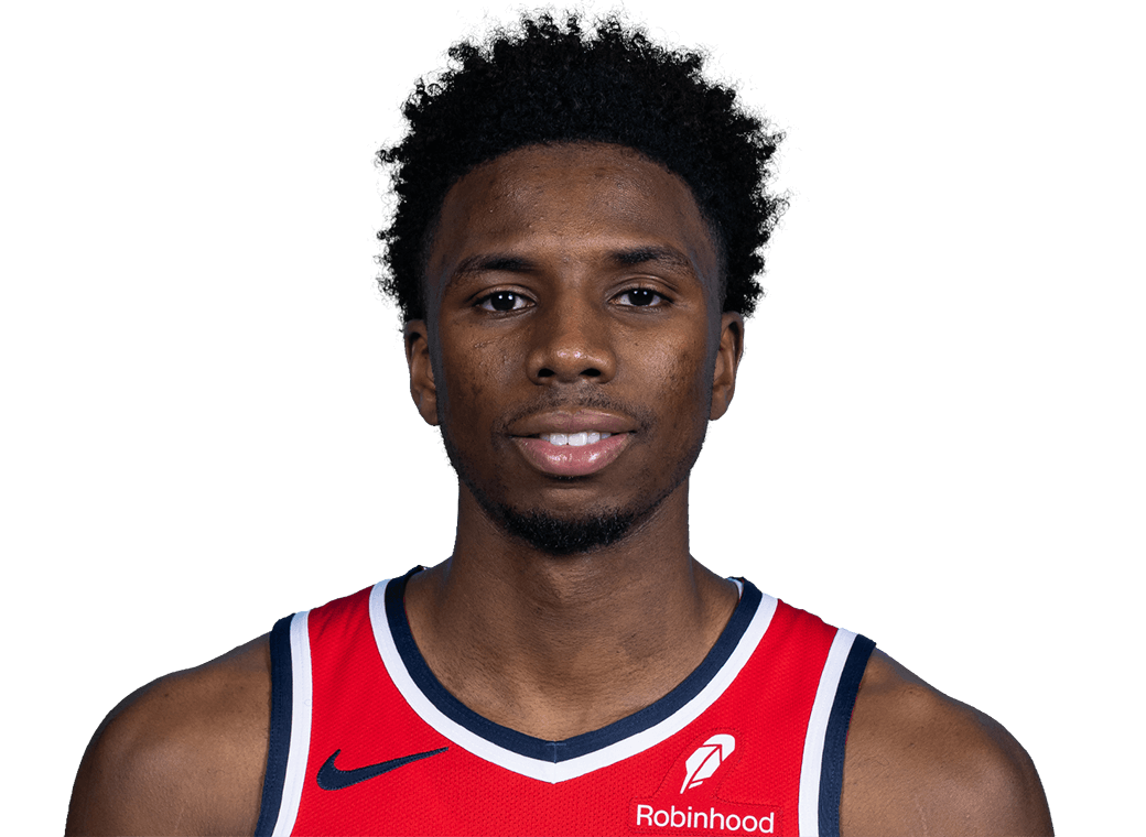 Portrait of a young Black male basketball player with a slight smile, wearing a red Washington Wizards jersey with a Nike logo and a Robinhood logo.