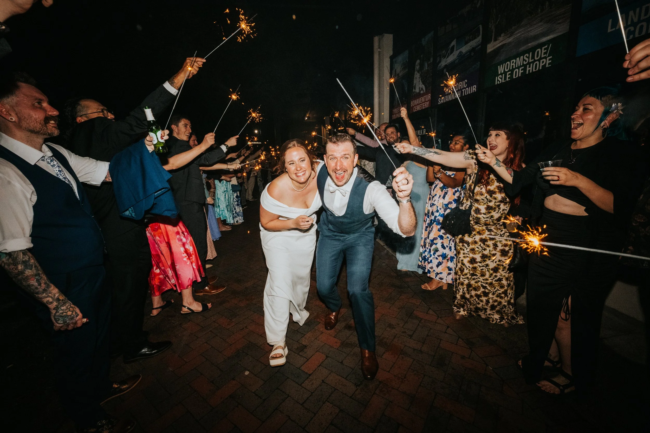 People celebrating at night with sparklers, dancing and smiling in a crowded outdoor setting.