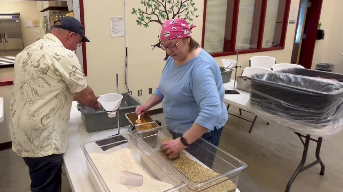 Volunteers measuring dry ingredients while packaging Nobody Goes Hungry stew mixes.