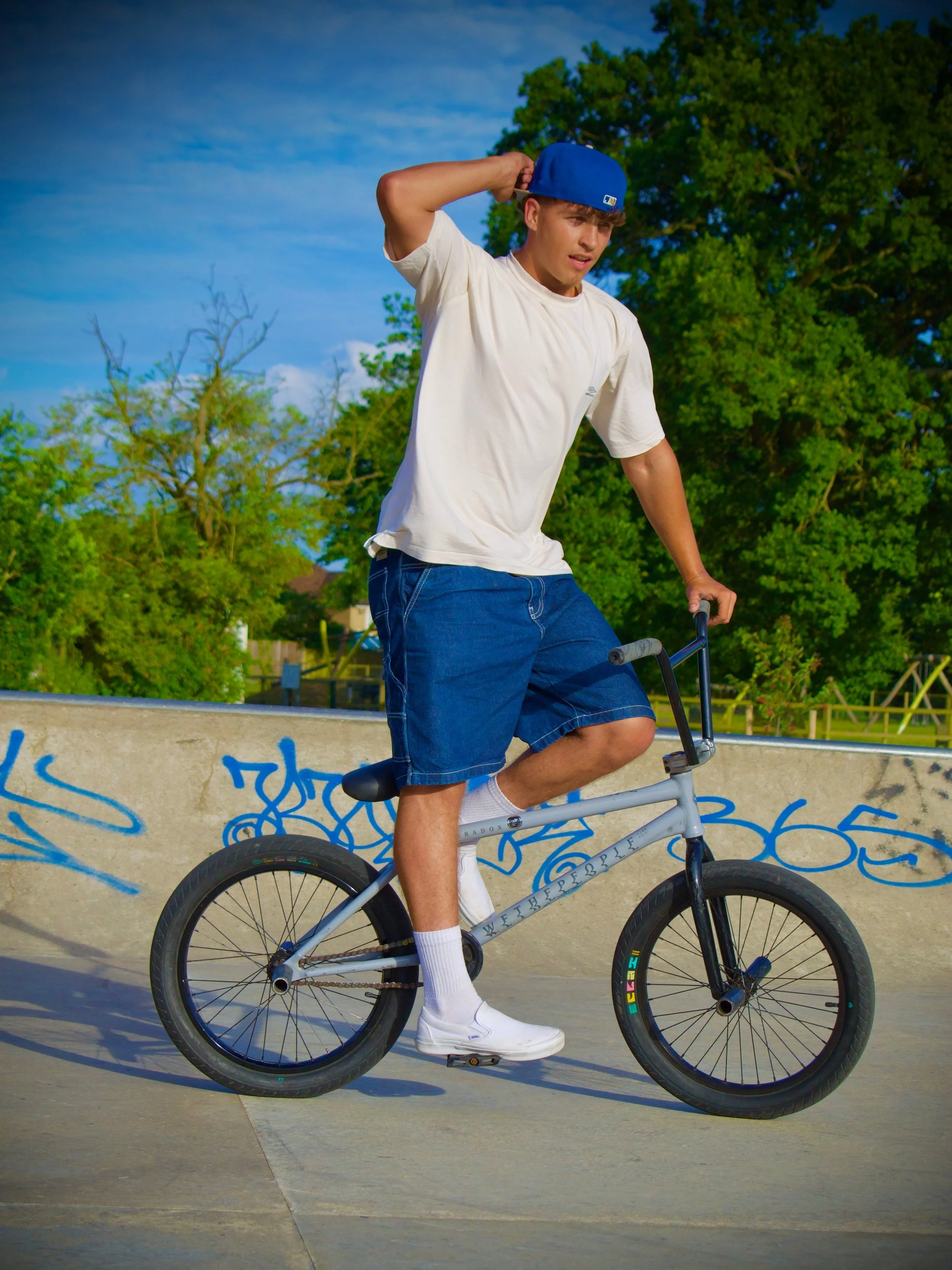 Male BMX rider in blue cap and shorts at skate park