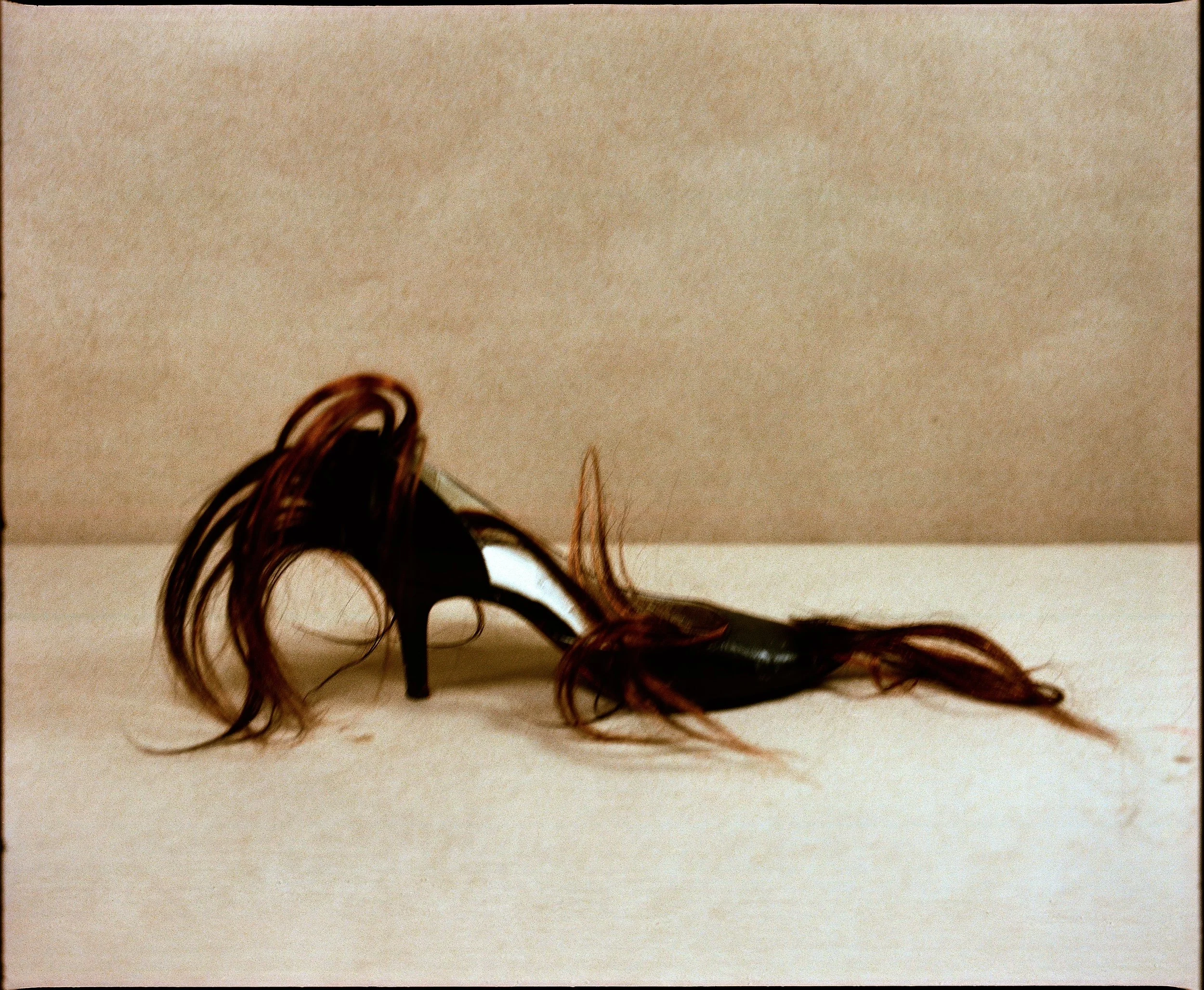 Close-up of a cluster of hair on a white surface with part of a person's head visible at the edge of the frame.