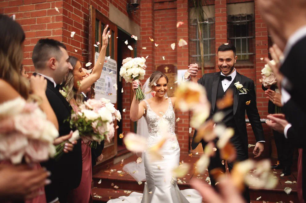 Greek wedding confetti exit at St Catherine’s Greek Orthodox Church, joyful bride and groom celebrating with family.