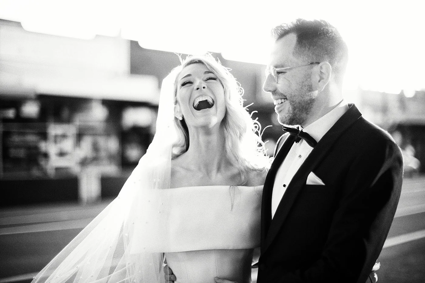 Black and white candid wedding photo of bride and groom laughing together after the ceremony, captured in a natural, emotional moment