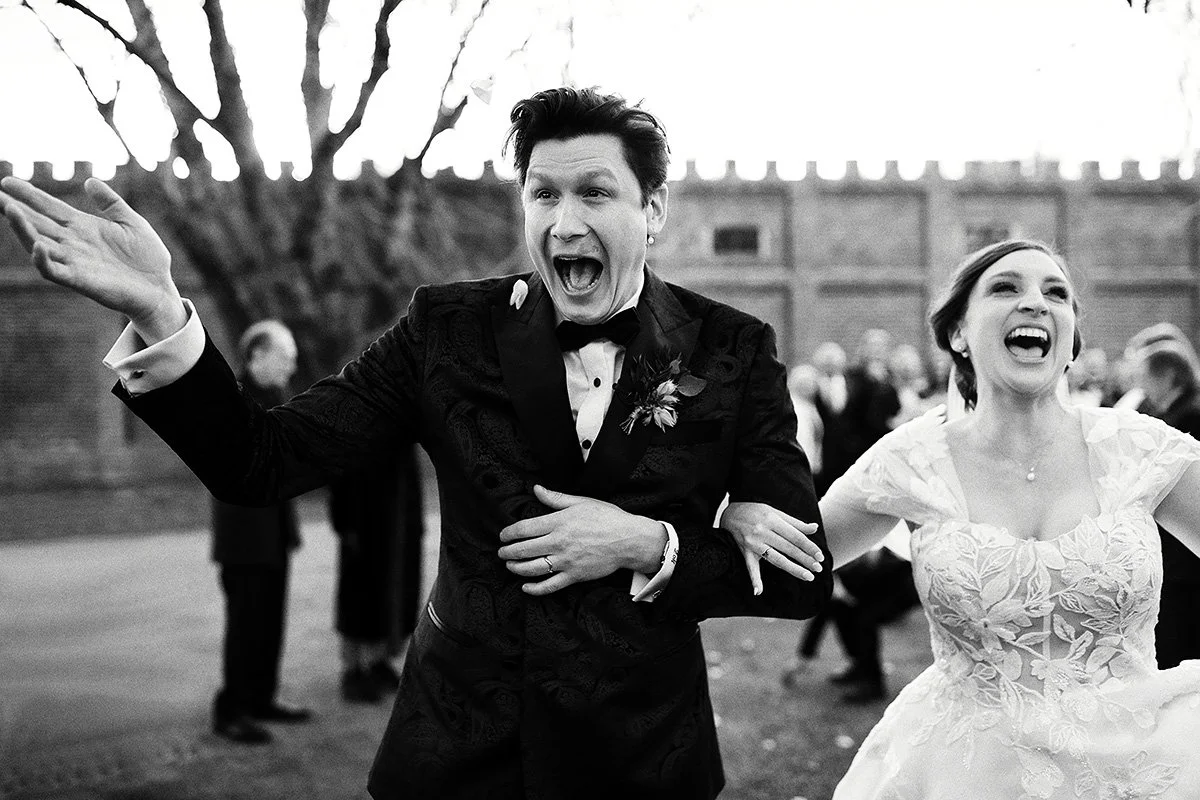 Bride and groom celebrating while walking out after their ceremony, joyful black and white candid wedding moment.