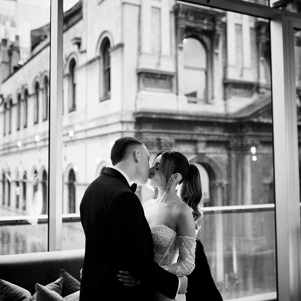 Bride and groom kissing by the floor-to-ceiling windows at Alto Events Melbourne wedding