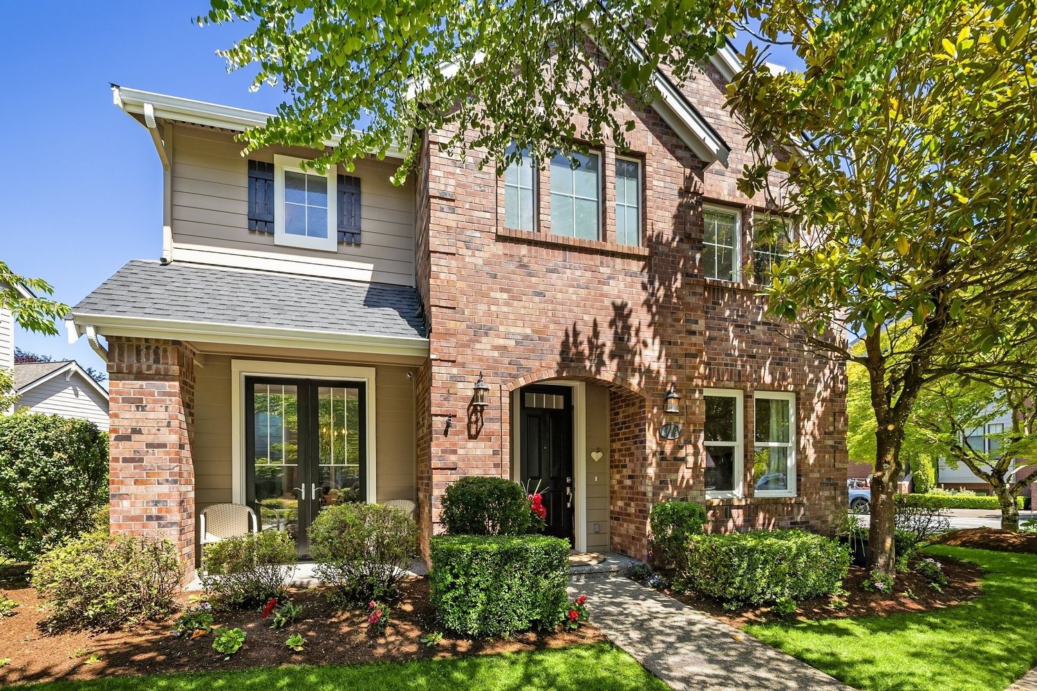 Elegant brick two-story home with lush landscaping, mature trees, and a welcoming front entrance.
