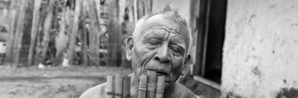 black and white photo of a Bolivian man playing a flute