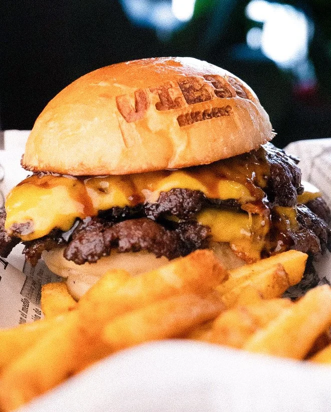 Hamburguesa con carne, queso y pan, acompañada de papas fritas.