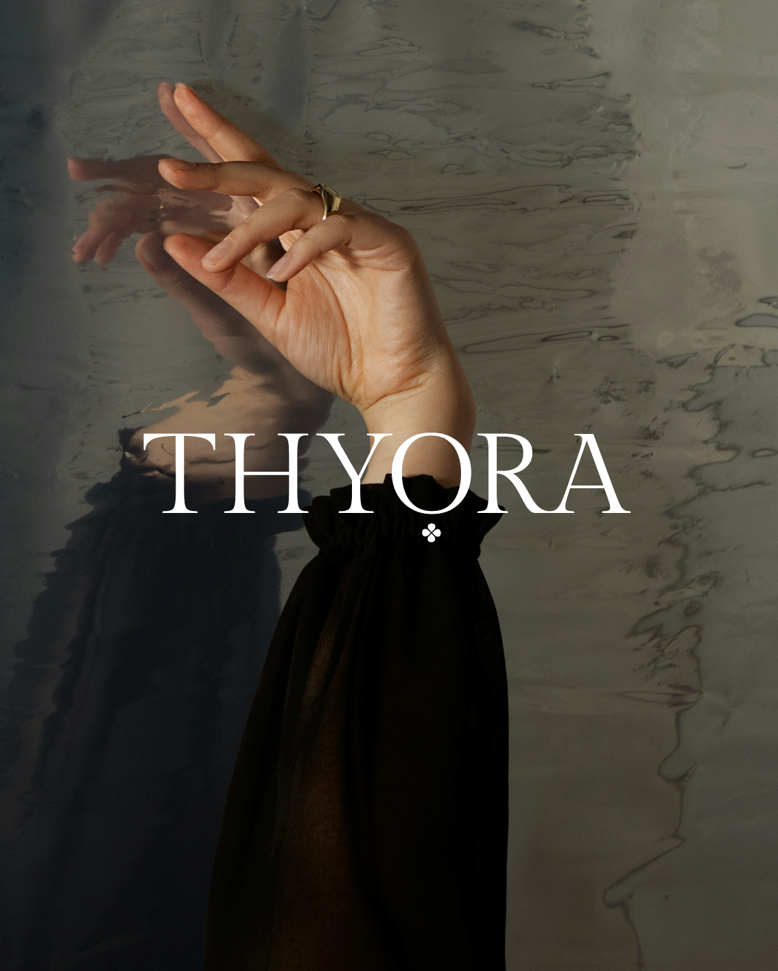 Mano con dedo indicador y medio en forma de señal enmarcada en reflejo en agua con superficie de mármol, con texto 'Thyora' en el centro.