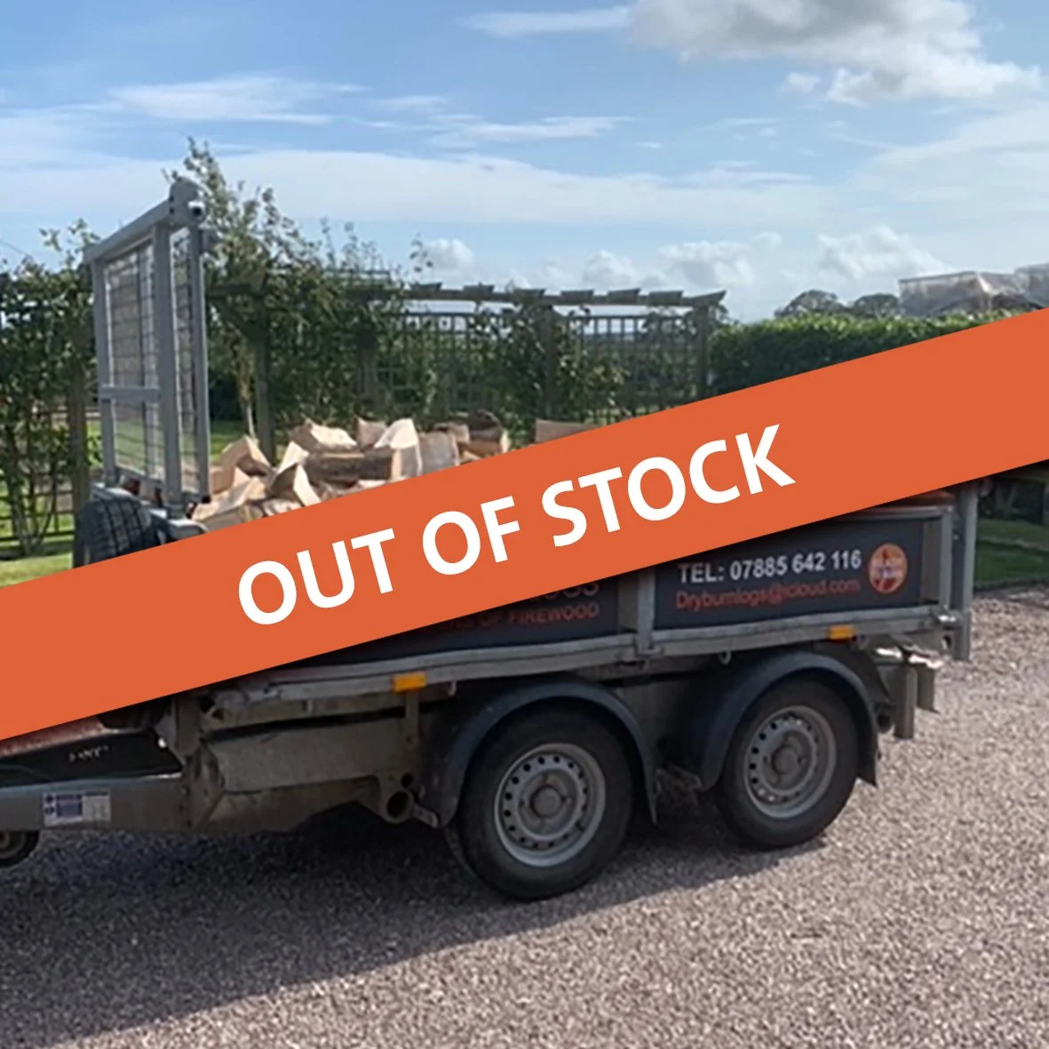 A trailer loaded with firewood from Dryburn Logs, parked on a gravel path. Trees and a wooden fence are visible in the background. The trailer bears a sign with contact details and imagery related to firewood supply.
