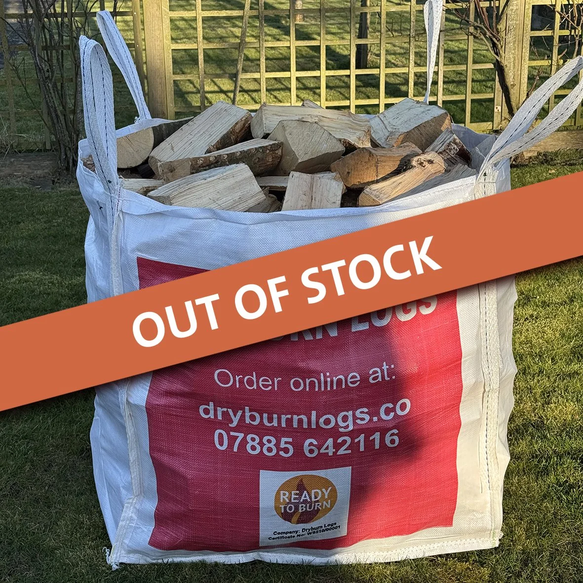 Large bulk bag filled with chopped firewood, labeled 'Dryburn Logs,' sitting on grass.