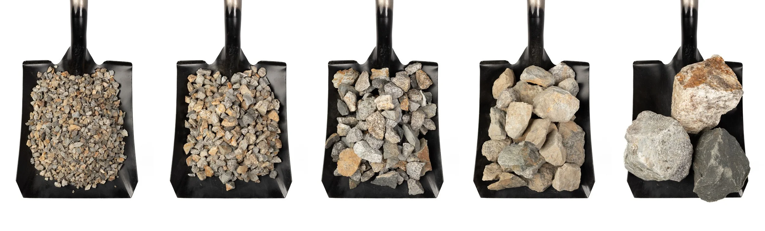 Five sizes of crushed stone and aggregate displayed on shovels, showing available construction aggregate products.
