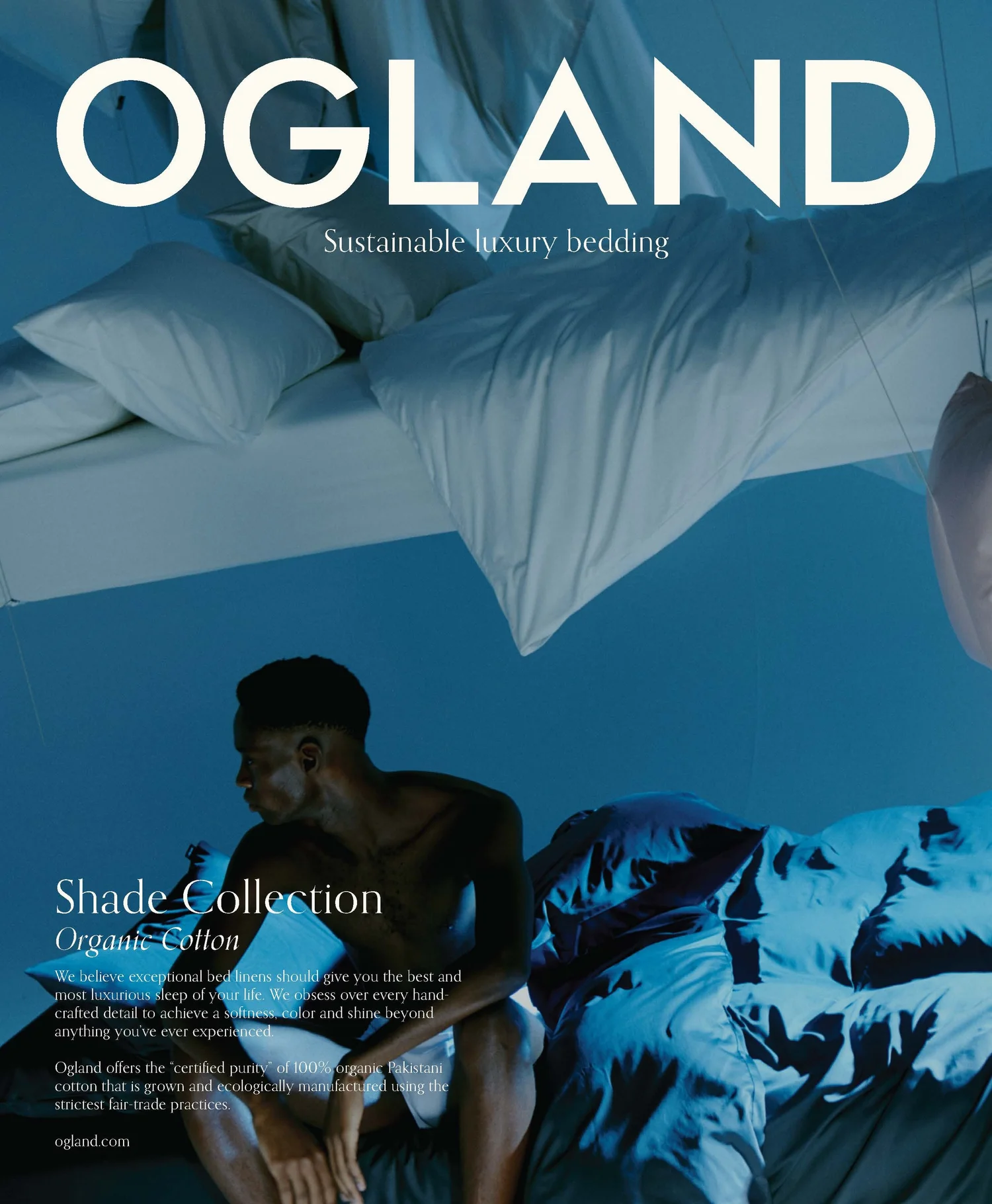 Cover of a bedding advertisement featuring a dark-skinned man sitting on a bed with blue and white sheets and pillows, with large white text that reads 'OGLAND' and smaller text that says 'Sustainable luxury bedding' and 'Shade Collection Organic Cotton.'