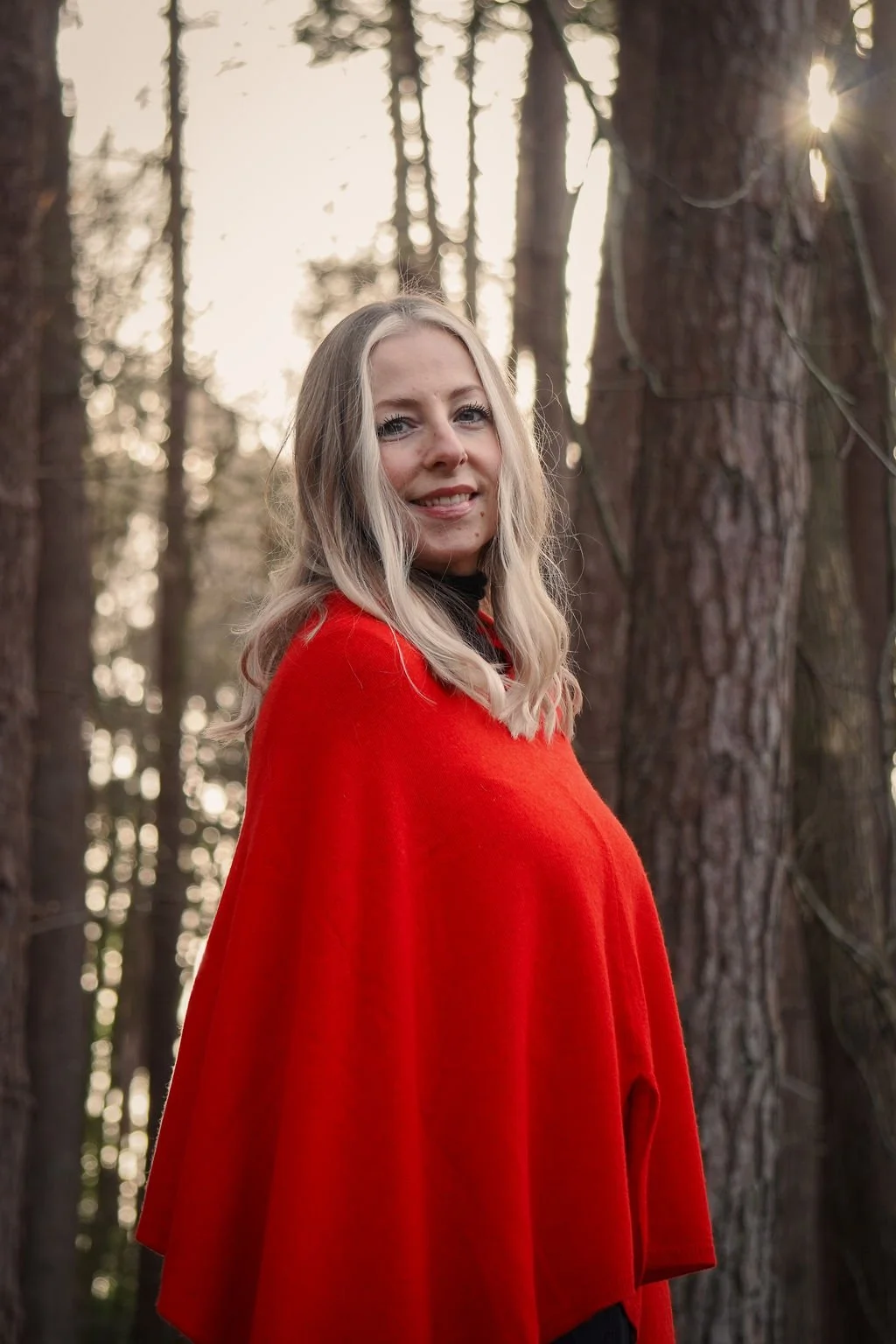 Woman sitting on a tan armchair, using a laptop, with a modern lamp and floral decor in the background. Lisa Jones Access Healing lts for Spinal Flow and Reiki healing in Hampshire.
