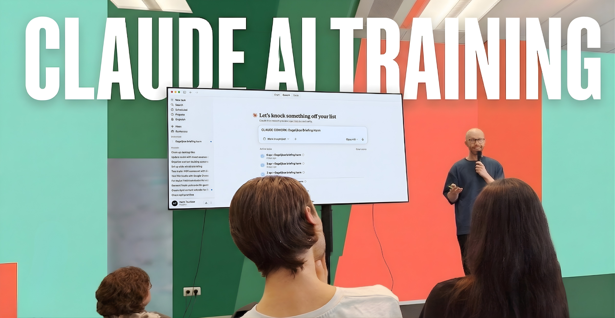 Een man geeft een presentatie aan een zaal met mensen. Op de achtergrond een groene en oranje muur met grote witte tekst 'CLAUDE AI TRAINING'. Op het scherm wordt een lijst met taken getoond.