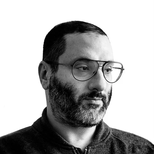 Black and white portrait of a man with glasses and a beard, looking to the side.