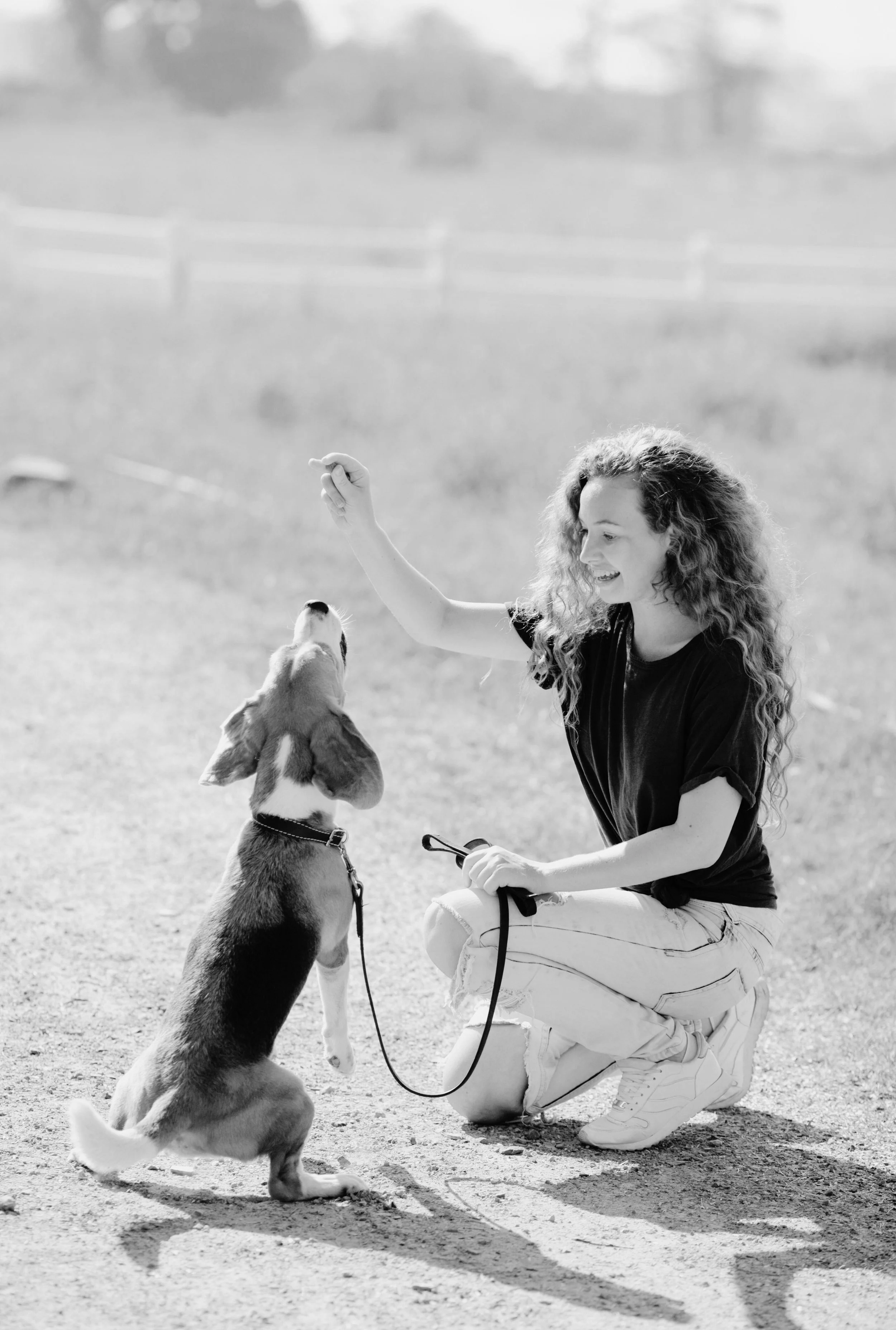 Woman training her dog, holding a treat encouraging her dog to look at her.