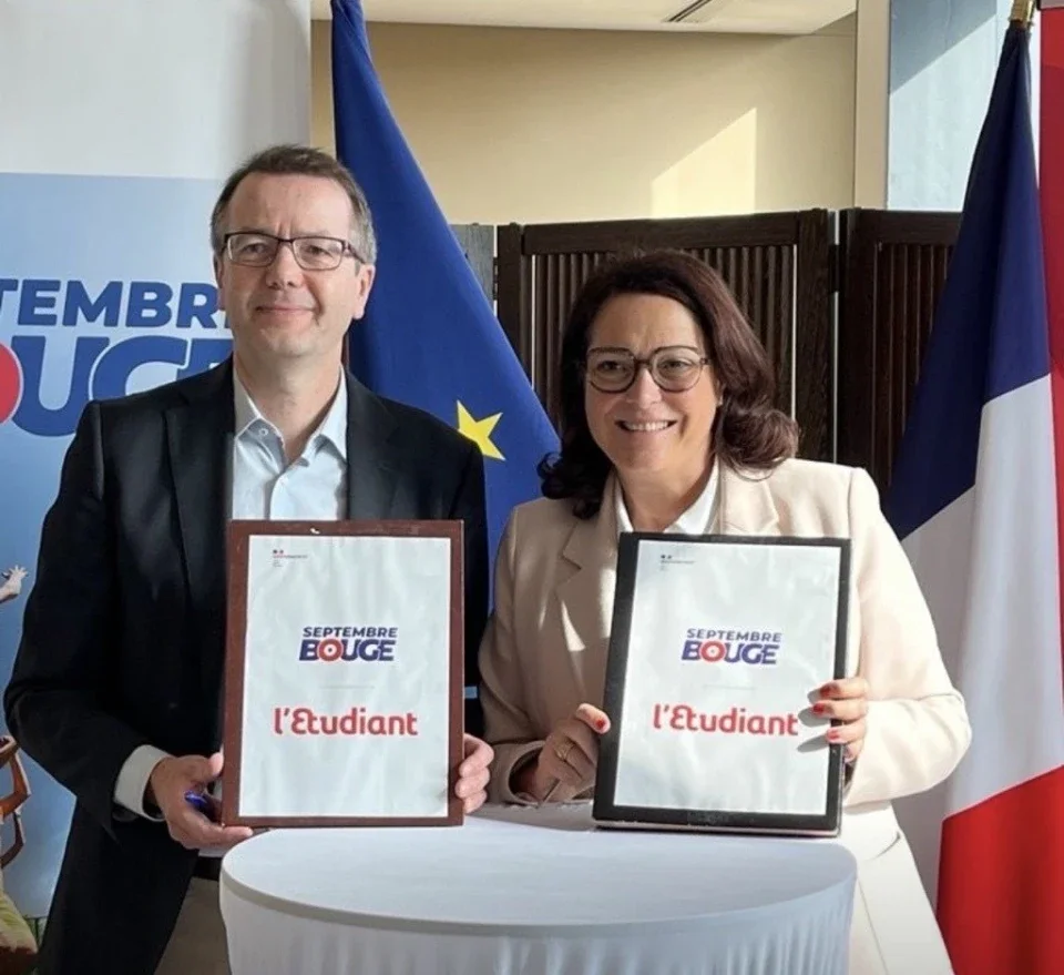 Deux personnes tenant des diplômes, devant un drapeau européen et un drapeau français, lors d'une cérémonie. l'Etudiant exposant site pro site corpo site commercial exposer au salon stand de l'Etudiant